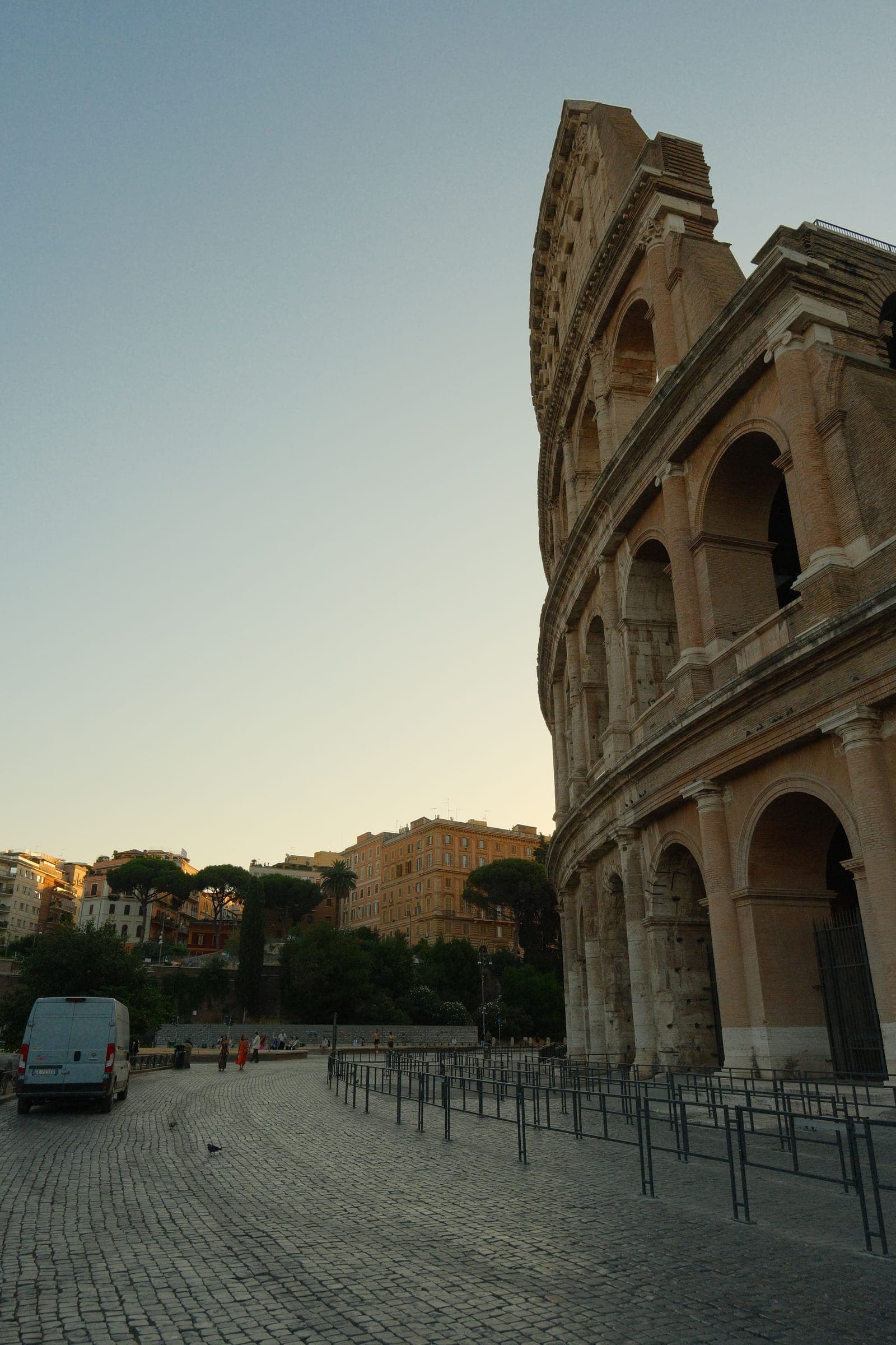 The Colosseum's ancient arches glowing at golden hour above a quiet cobblestone plaza in Rome