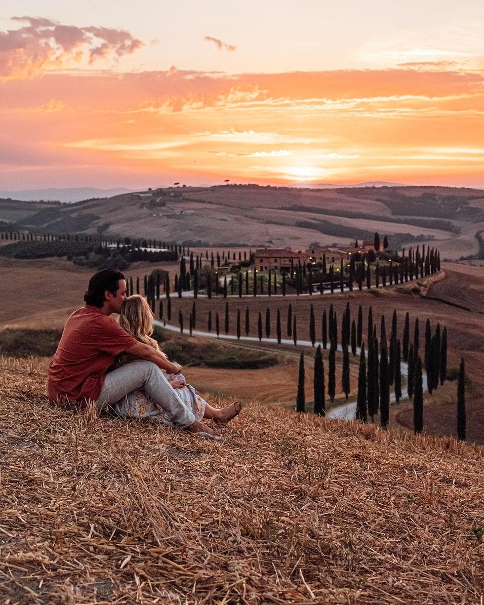 A couple watching the sunset over Tuscany's cypress-lined hills