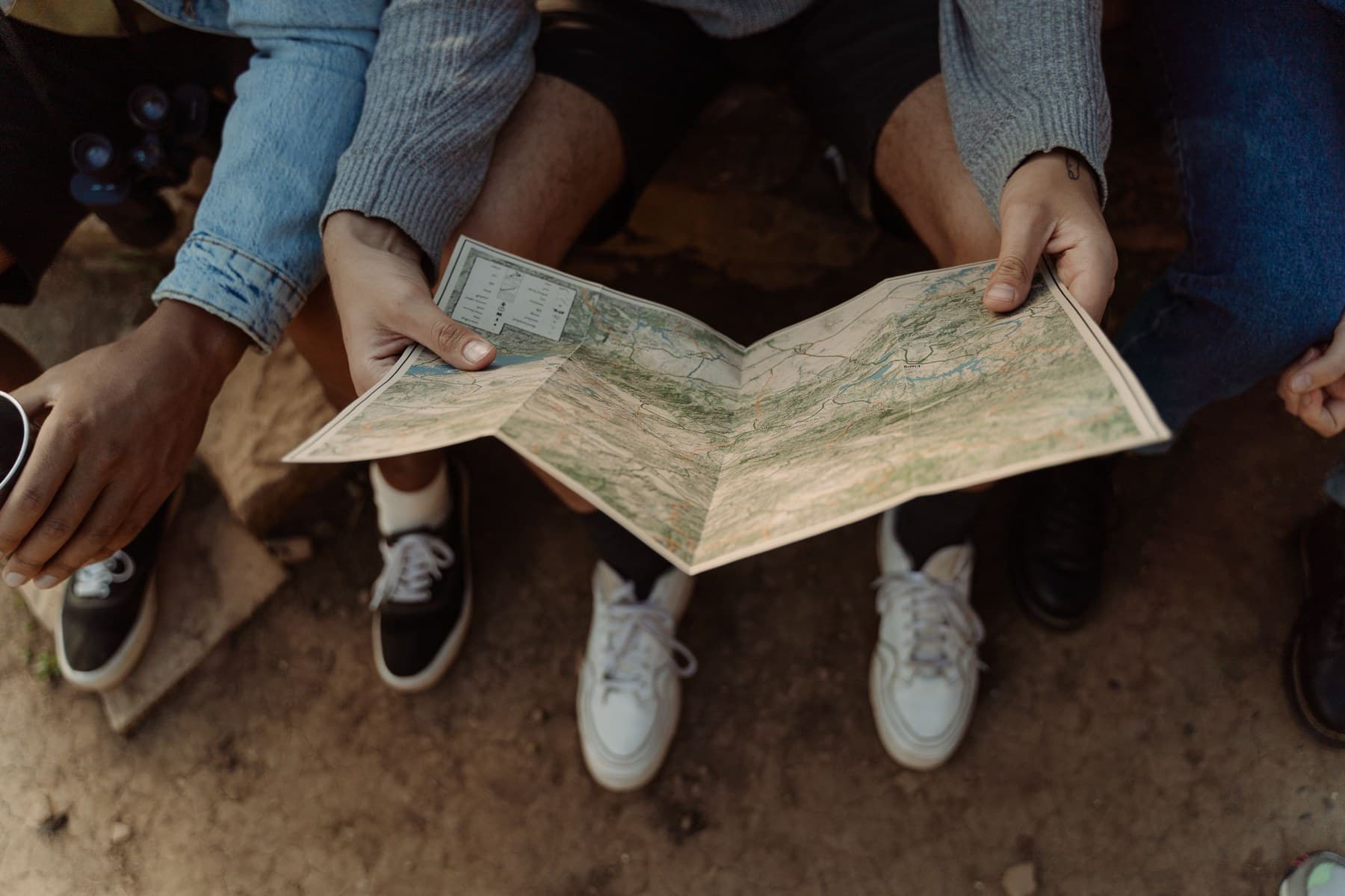 Travelers using a paper map while sitting outdoors